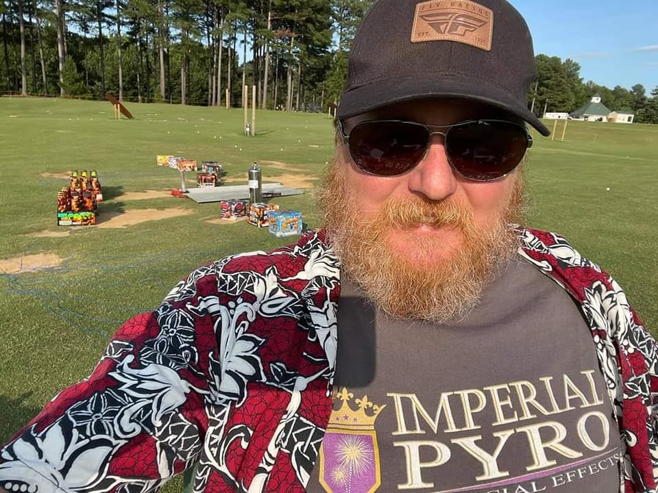 Crew member on site with consumer fireworks racks staged at a golf course