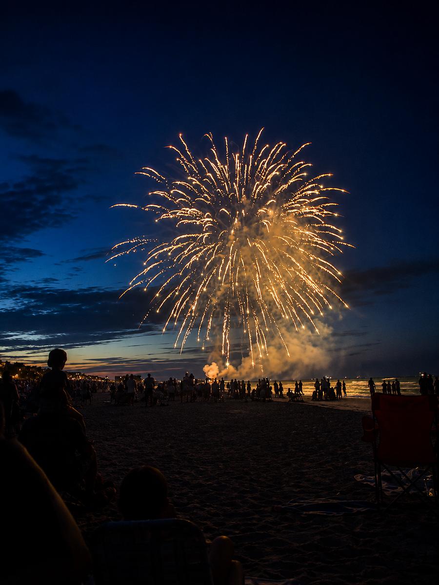 Golden fireworks bursting over the water at an Imperial Pyro show