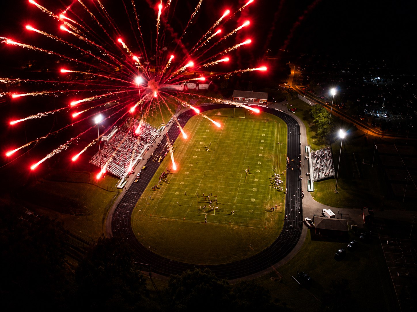 Aerial fireworks shells bursting over a stadium at night
