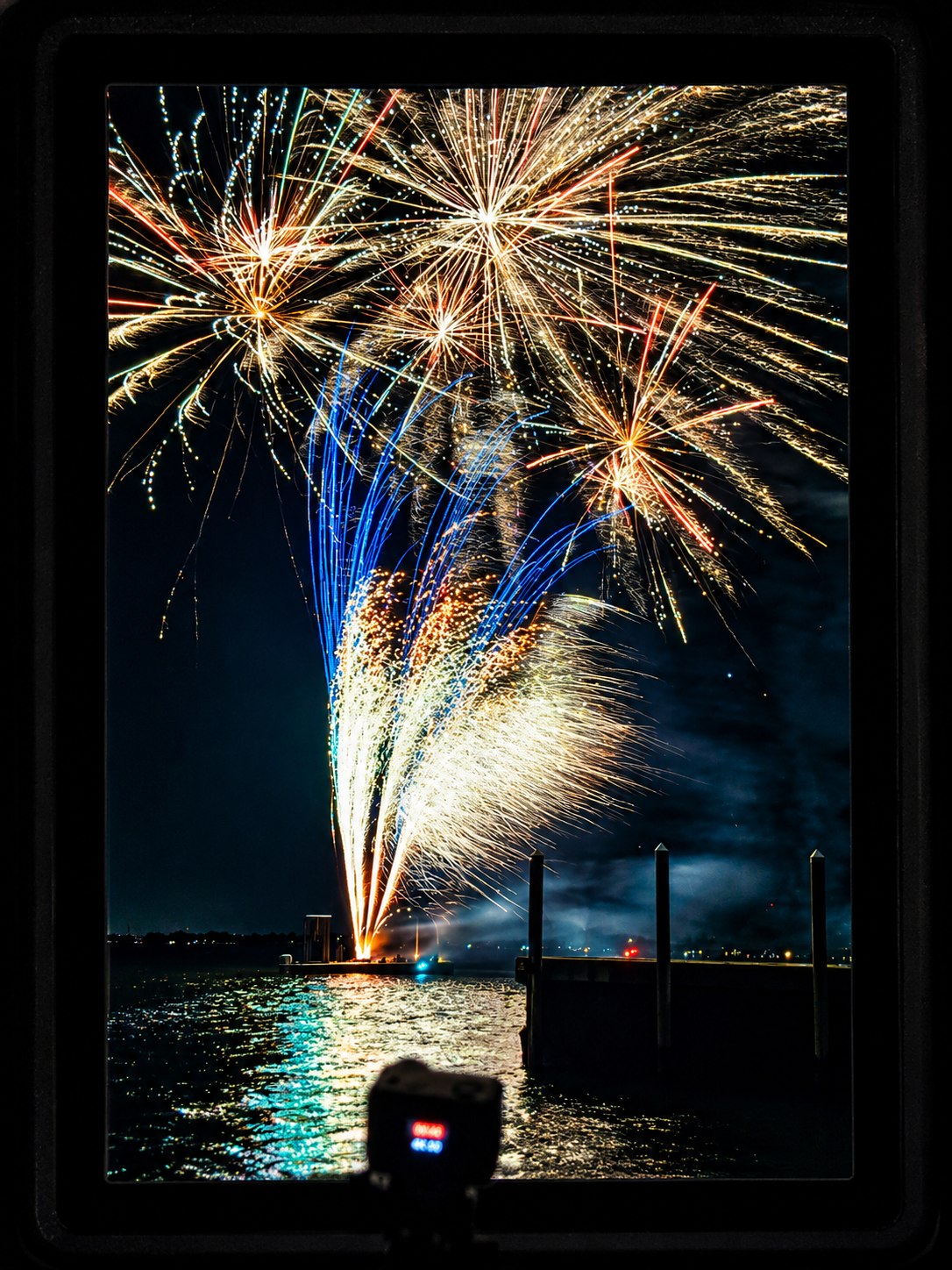Fireworks firing from a barge on the water at a yacht club