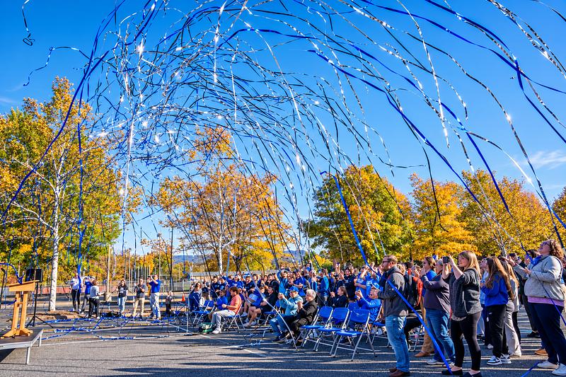 Blue and silver streamers arcing over an outdoor crowd on a sunny day