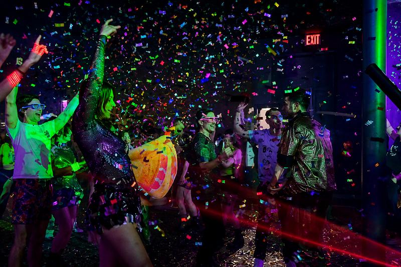 Confetti falling over a party crowd with lasers and colorful lights at night